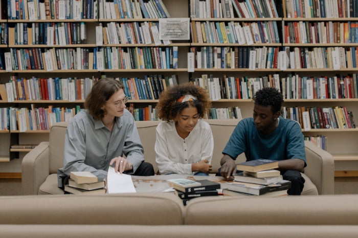 three friends reading inside a library